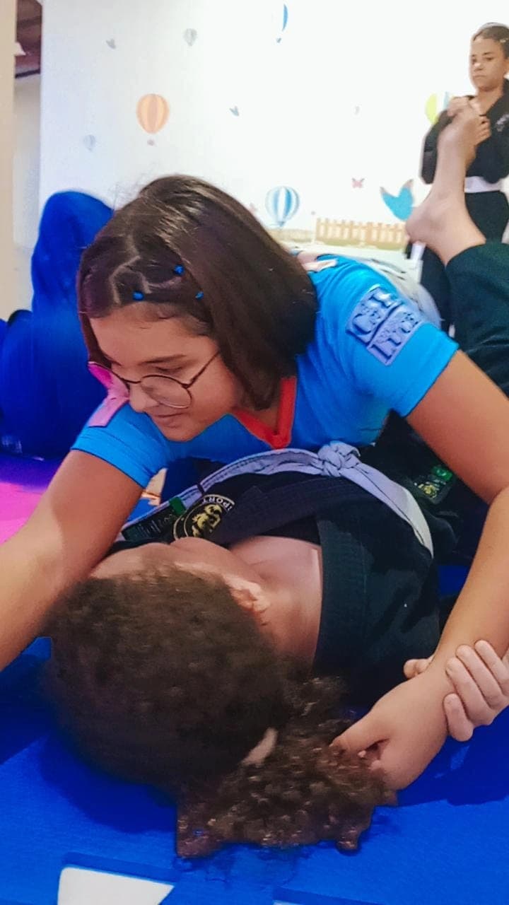 Aluna orientando um colega mais novo durante treino de Jiu-Jitsu no tatame do Colégio Baby Avançar