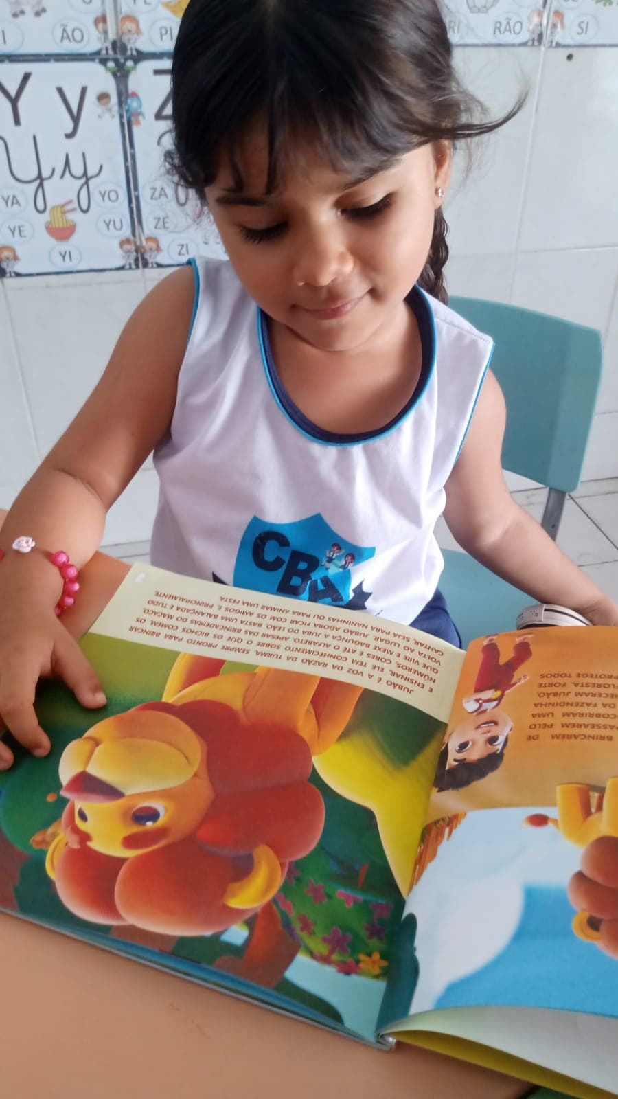 Criança da Educação Infantil lendo um livro ilustrado em sala de aula
