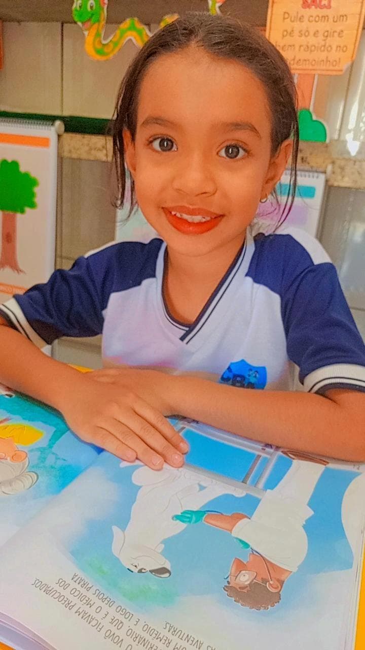 Aluna do Colégio Baby Avançar sorrindo durante atividade de leitura em sala de aula